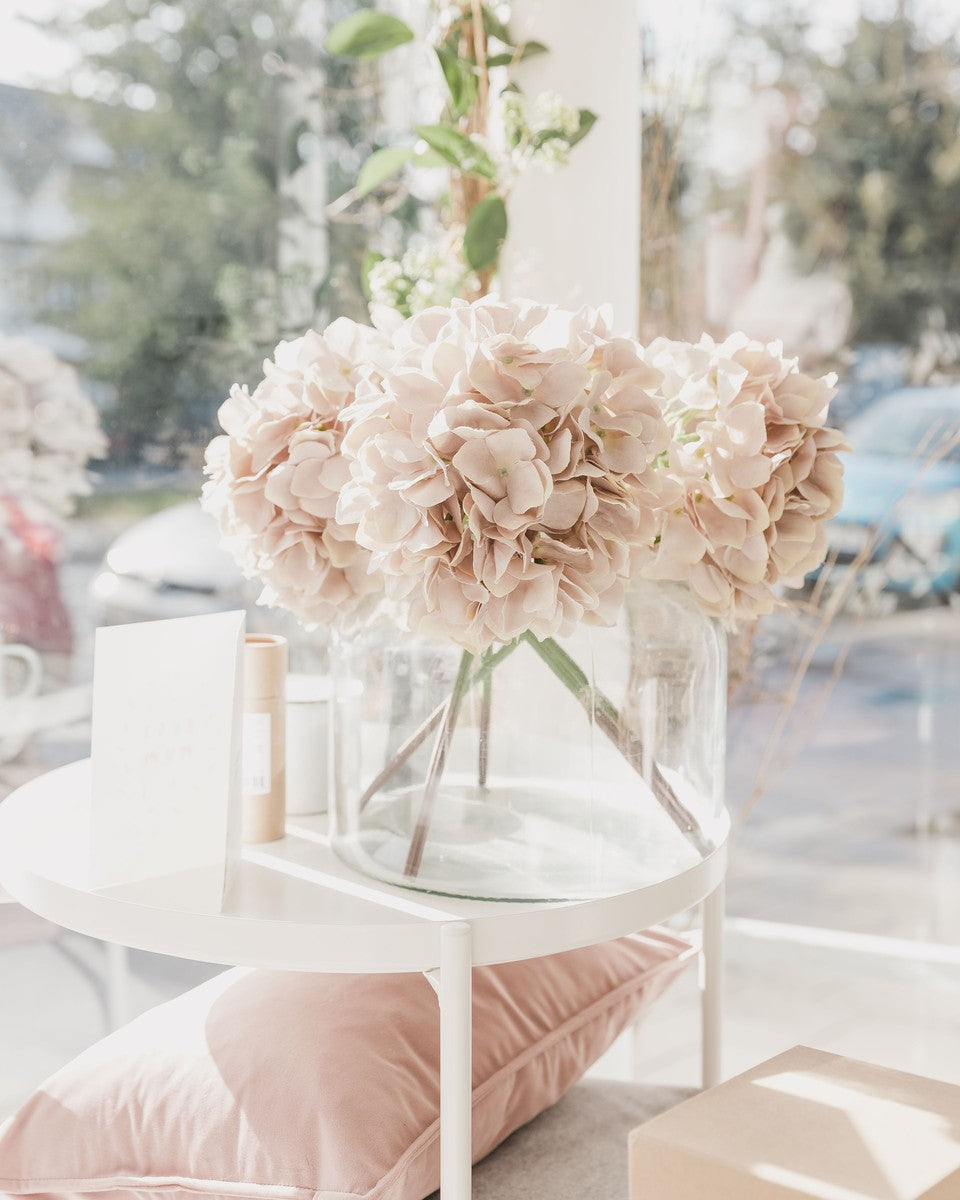 Blush pink flowers in a vase in a sunny shop window