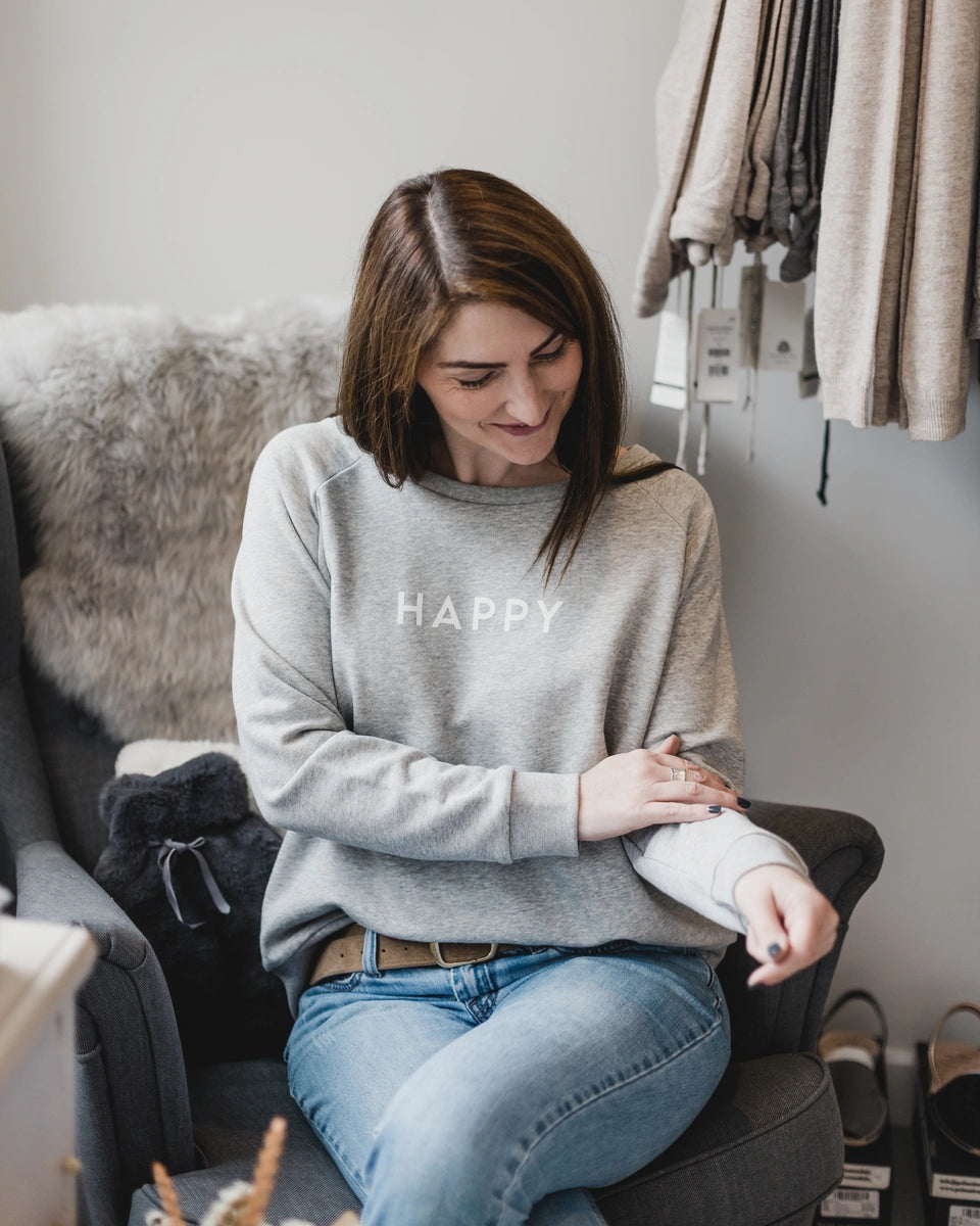 Suzie, owner of SELF, sat on the floor with her legs folded to the side holding a warm mug of tea and smiling at the camera